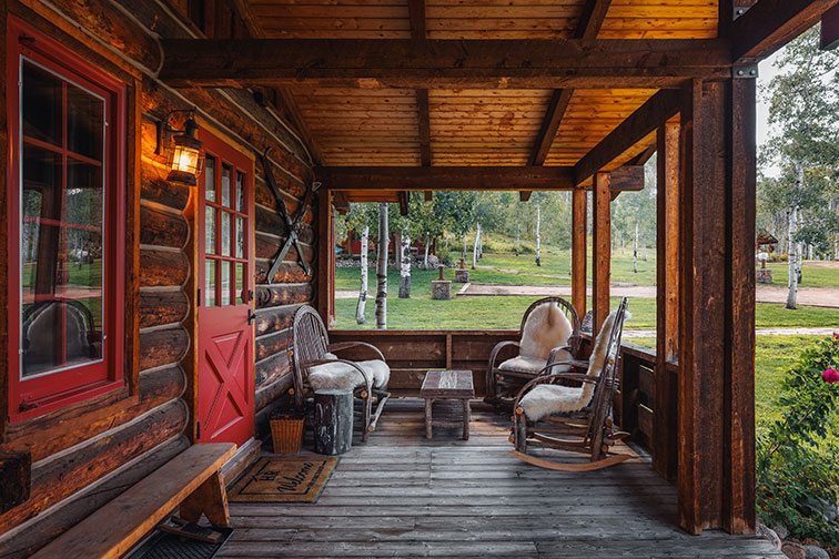 A porch of a cozy guest cabin with rustic charm at The Home Ranch in Colorado.