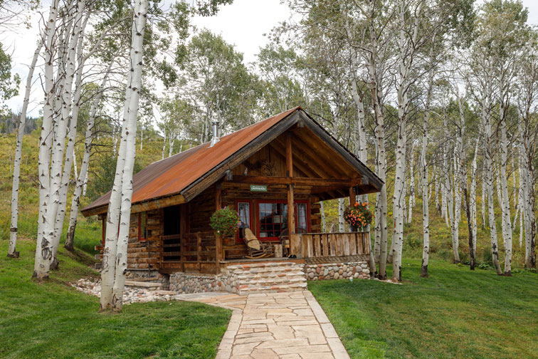 Exterior and stone walkway of a cozy hideaway cabin at The Home Ranch in Colorado.