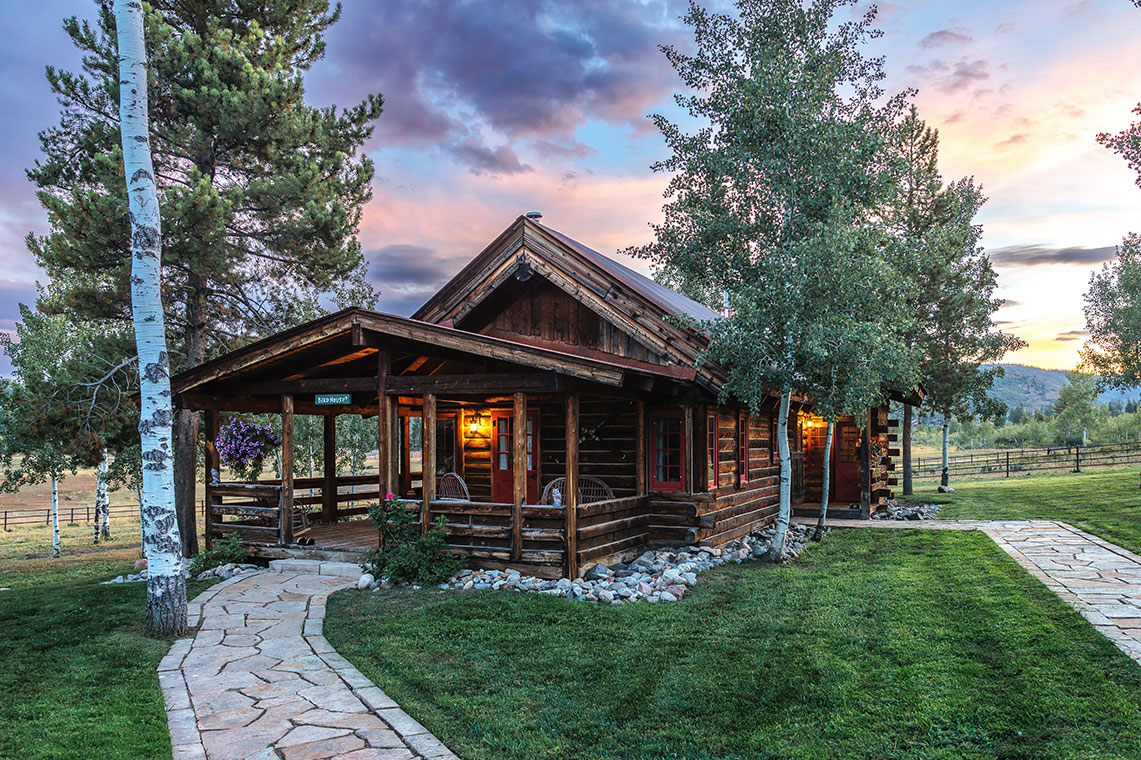 The Birdhouse guest cabin is an intimate retreat for couples and solo adventurers, this red-windowed log cabin boasts a comfy full-size bed and stirring views of a picturesque pond and the surrounding natural environs.