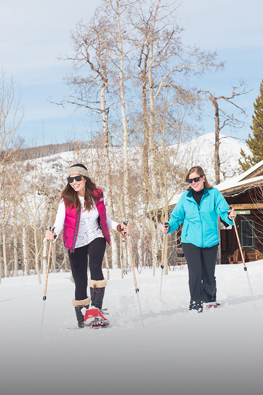 Two women snowshoeing during an outdoor expedition at The Home Ranch in Clark, Colorado.