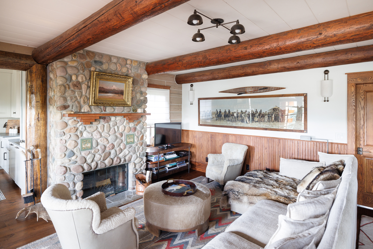 A cozy stone fireplace anchors a light-filled living area at the Columbine family guest cabin at The Home Ranch in Colorado.