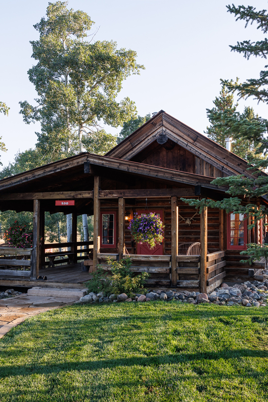 With its quaint red windows and doors, this thoughtfully appointed log cabin at The Home Ranch in Colorado offers an expansive deck that runs along the length of the residence.