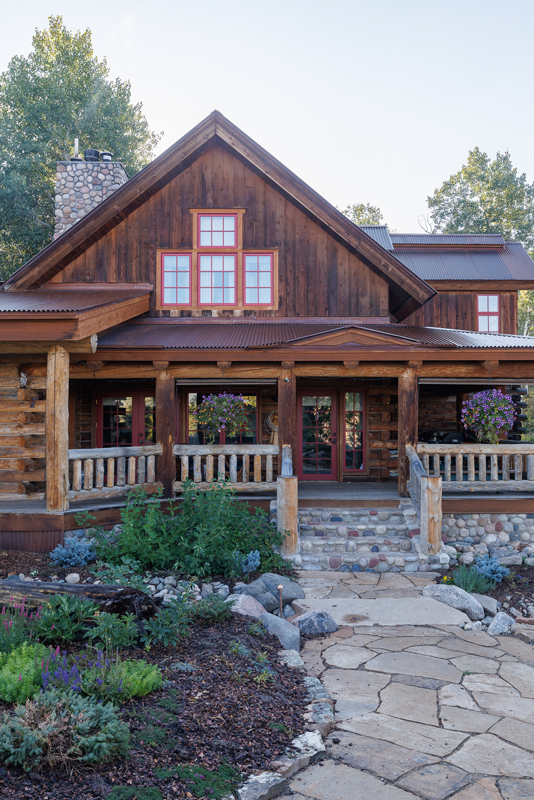 A front porch adorns the exterior of the rustic-luxe guest house at The Home Ranch in Colorado.