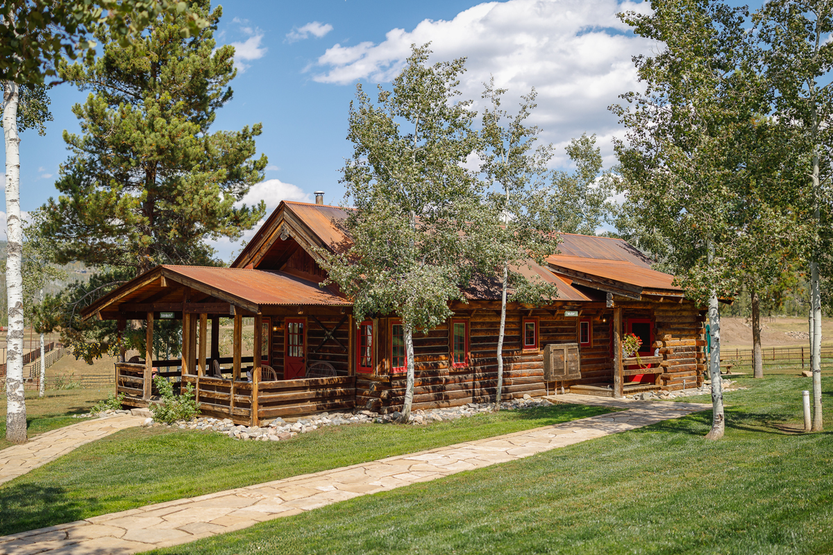 An intimate retreat for couples and solo adventurers, this red-windowed log cabin boasts a comfy full-size bed and stirring views of a picturesque pond and the surrounding natural environs at The Home Ranch in Colorado.