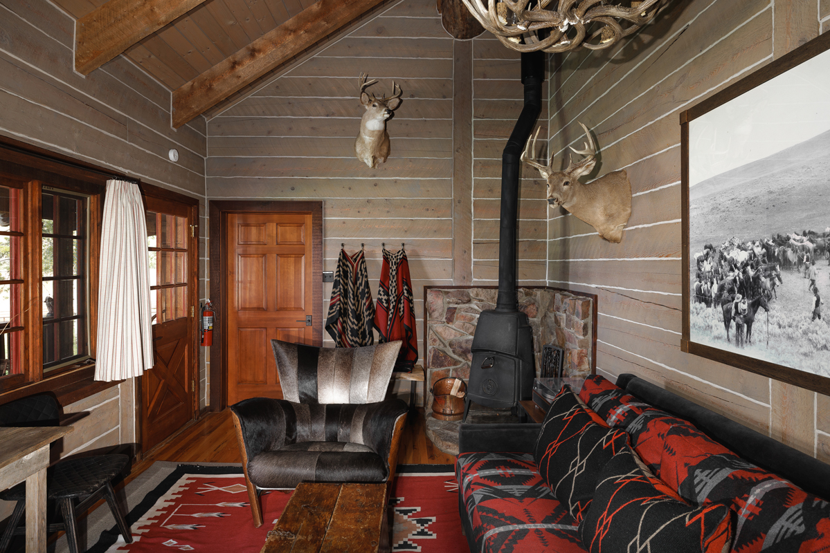 An antler chandelier, a wood-burning fireplace, and other nature-inspired decor adorns this guest cabin at The Home Ranch in Colorado.