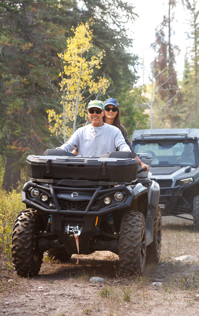 A couple rides four-wheelers during an authentic outdoor experience, which is perfect for group outings and events at The Home Ranch.