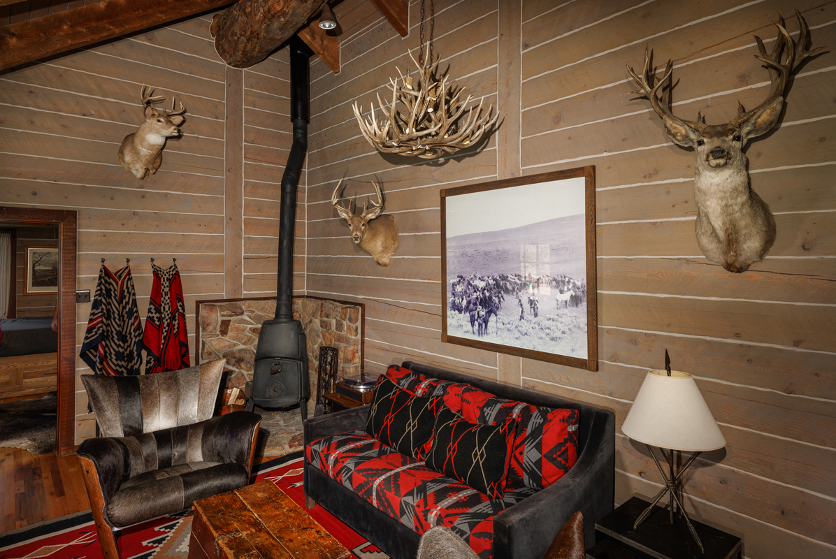 An antler chandelier, a wood-burning fireplace, and other nature-inspired decor adorns this guest cabin at The Home Ranch in Colorado.