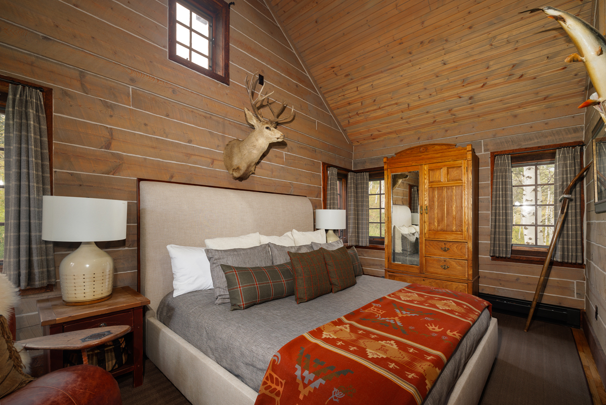 The serene bedroom of the Compromise guest cabin at The Home Ranch in Colorado is awash in earth tones, including its nature-inspired décor.