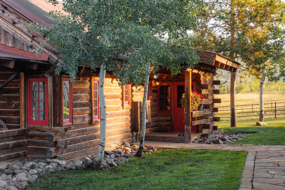 The Home Ranch in Colorado offers cozy guest cabins with rustic charm. This cabin has a welcoming front porch and a cozy exterior that will make you feel right at home.