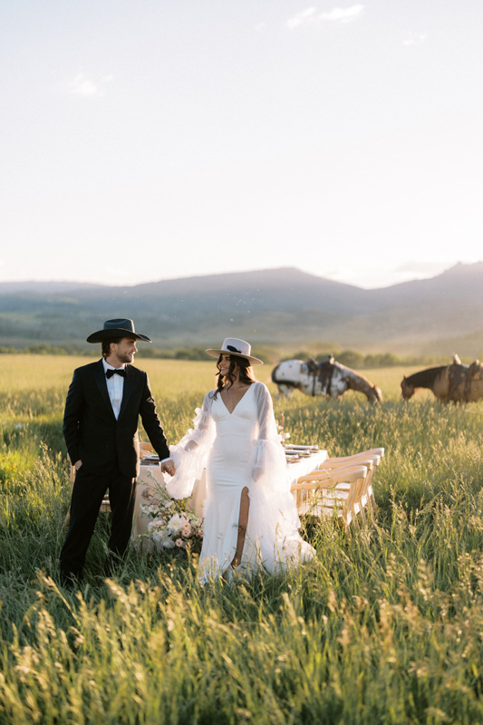 bride and groom in a wide open field with horses