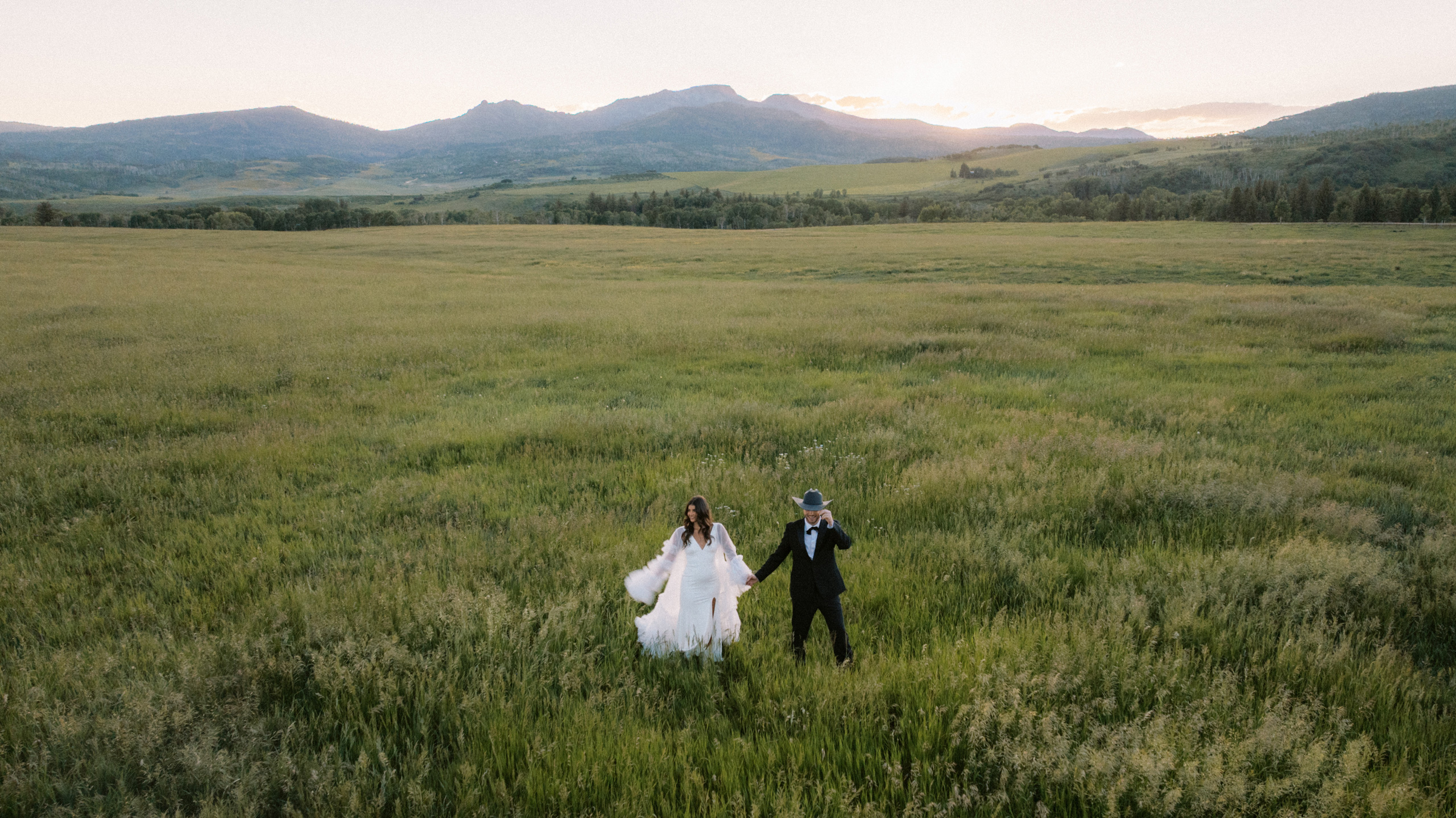 bride and groom dancing in a wide open field with mountain backdrop