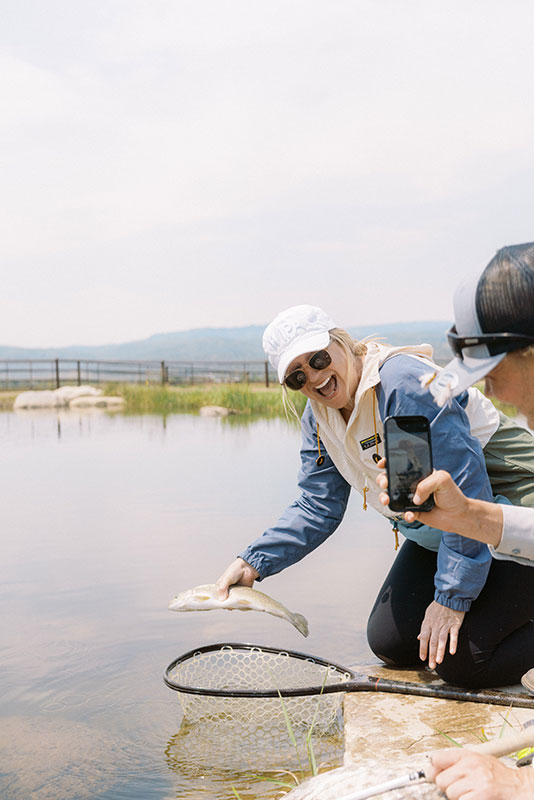 Woman fishing at pond in The Home Ranch luxury, western ranch in Clark, Colorado.