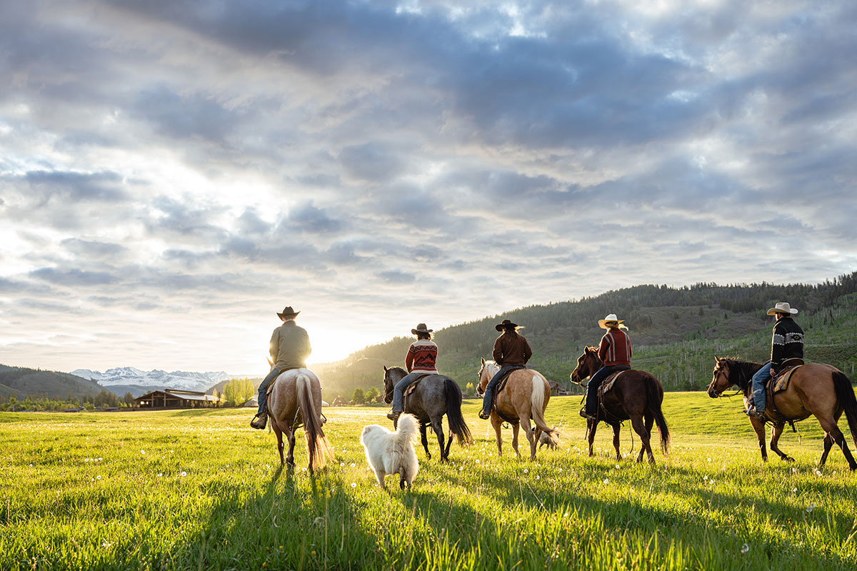 Group of horseback riders at sunset at The Home Ranch in Colorado.